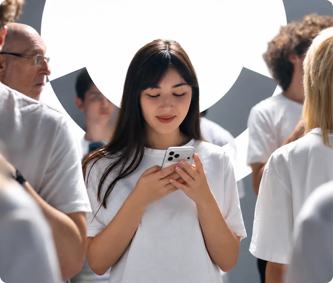 A woman smiling at her phone in a crowd